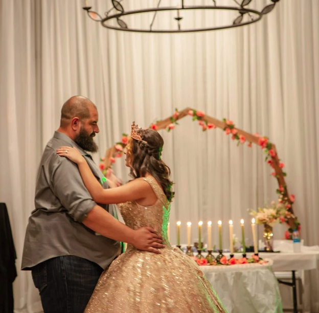 Father daughter dance beneath the iron chandelier in front of the floral arch
