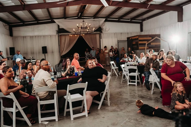 Guests seated at the reception listening to toasts in the draped indoor hall