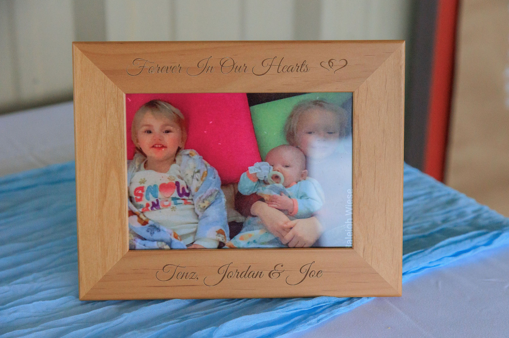 Jaelyn & Keelan's wedding at Reverie at Diamond D — a "Forever In Our Hearts" memorial frame displayed at the reception