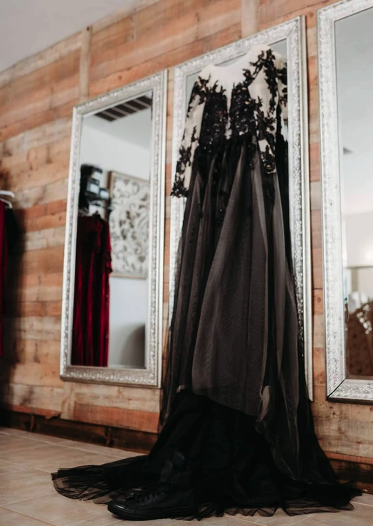 Black lace wedding gown hanging against the shiplap wall and silver mirrors in the bridal suite
