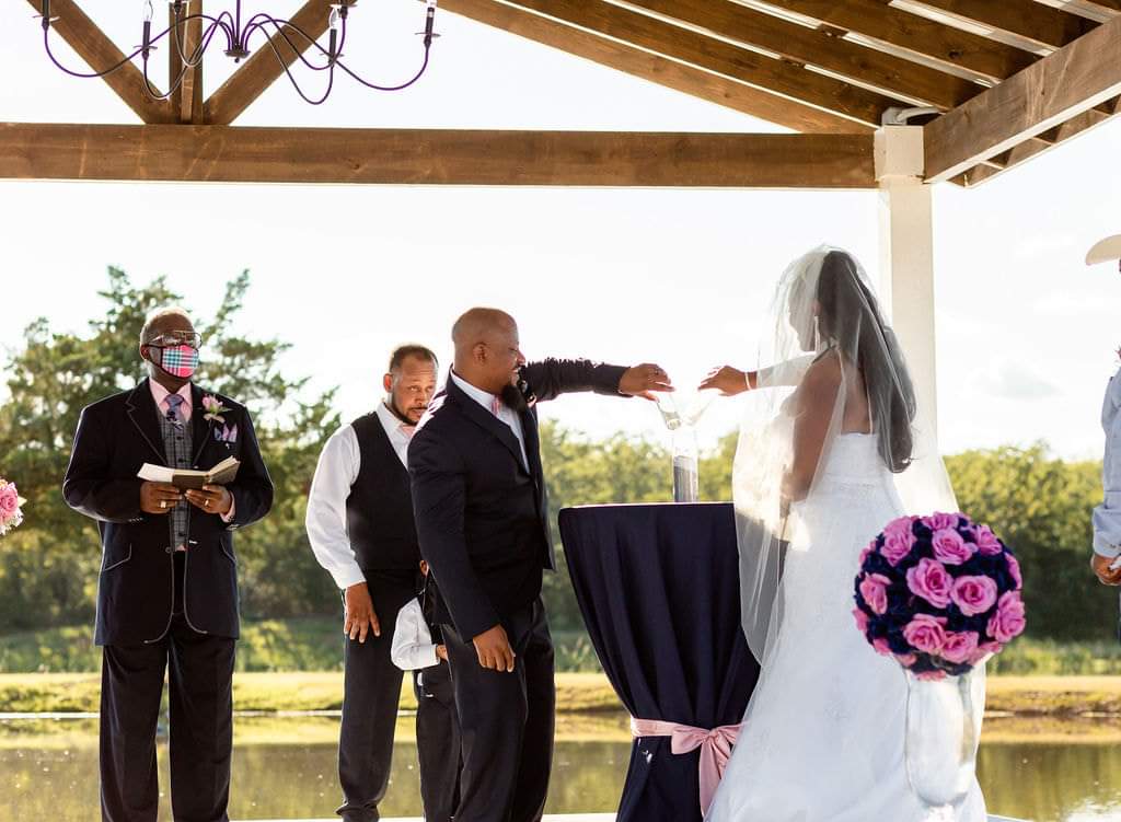 Bride and groom performing a unity sand ceremony on the lakeside pavilion