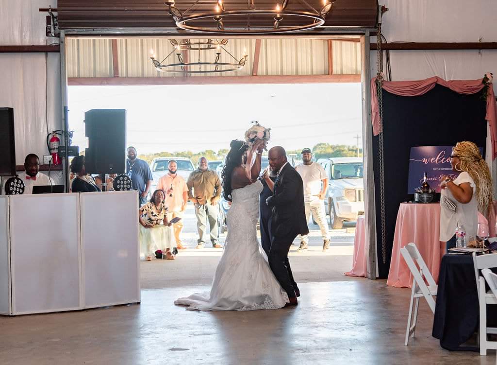 Bride and groom dancing together in the open barn doorway
