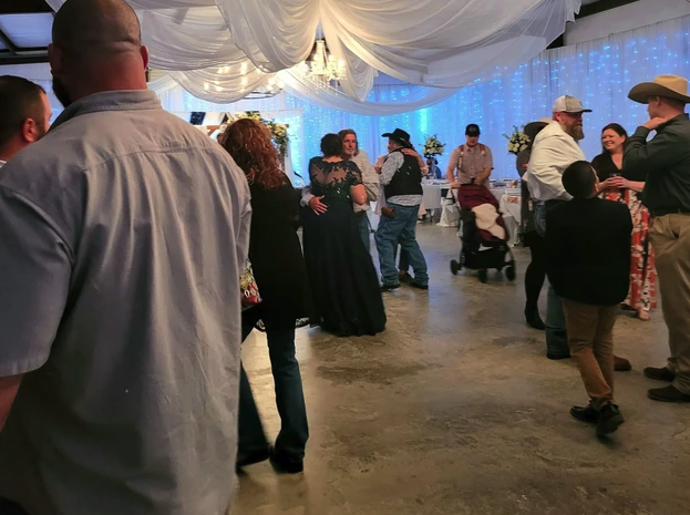 Guests visiting and dancing on the barn floor beneath white ceiling draping and twinkle lights