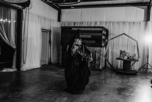Black and white wide shot of the couple's first dance in the draped reception hall