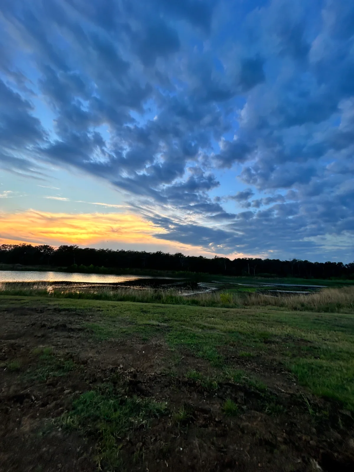Sunset over the nine-acre stocked lake and open pasture grounds at Reverie at Diamond D in Normangee, Texas