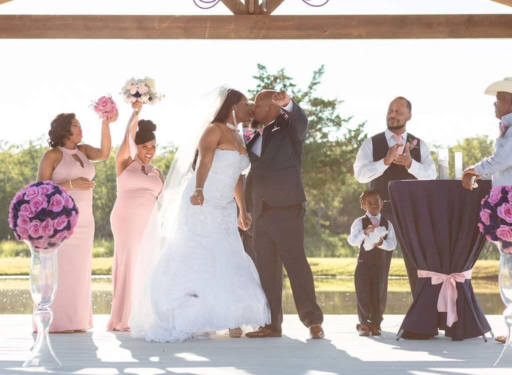 Bride and groom's first kiss on the lakeside pavilion at Reverie at Diamond D in Normangee, Texas