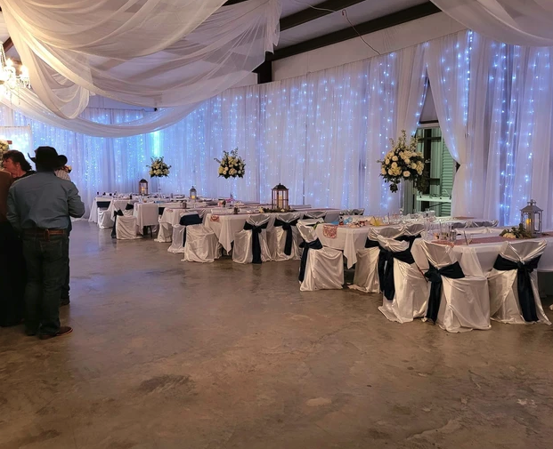 Reception tables with navy sashes and floral centerpieces inside the draped barn