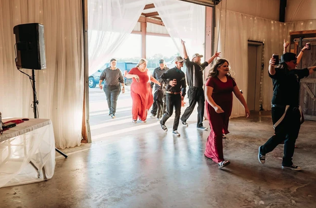 Guests dancing into the reception through the open barn doors during the grand entrance