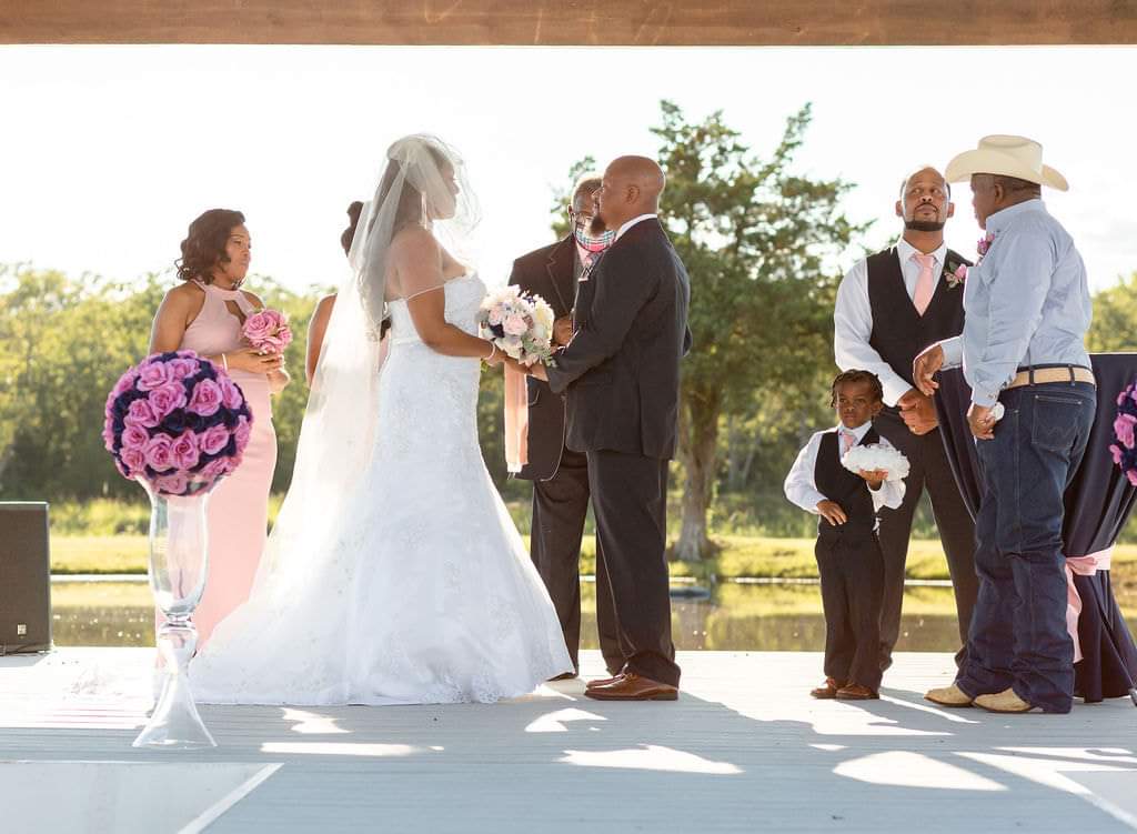 Couple exchanging vows on the lakeside pavilion with their wedding party