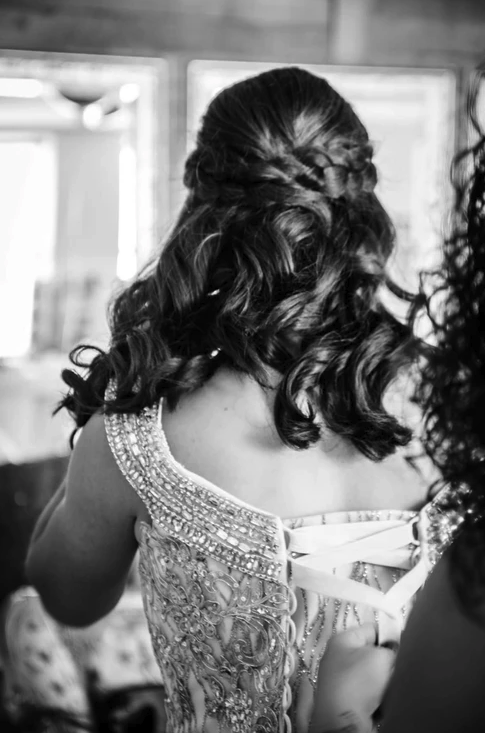 Black and white detail of the beaded gown corset being laced in the getting ready suite