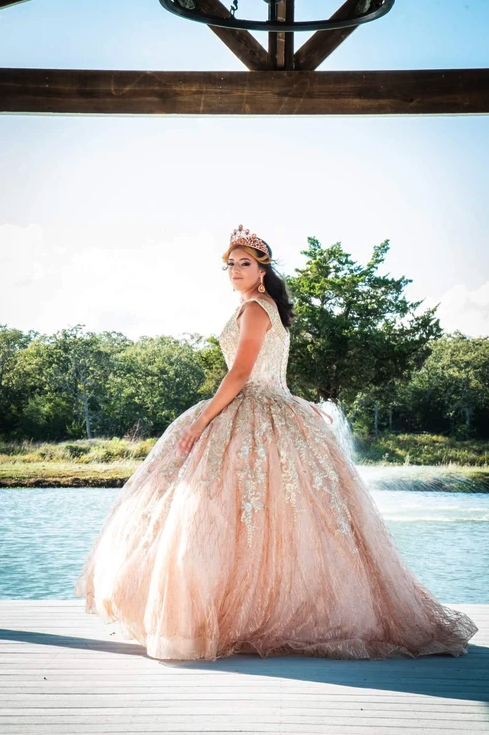 Sweet 16 honoree in a rose gold ball gown on the lakeside pavilion at Reverie at Diamond D in Normangee, Texas