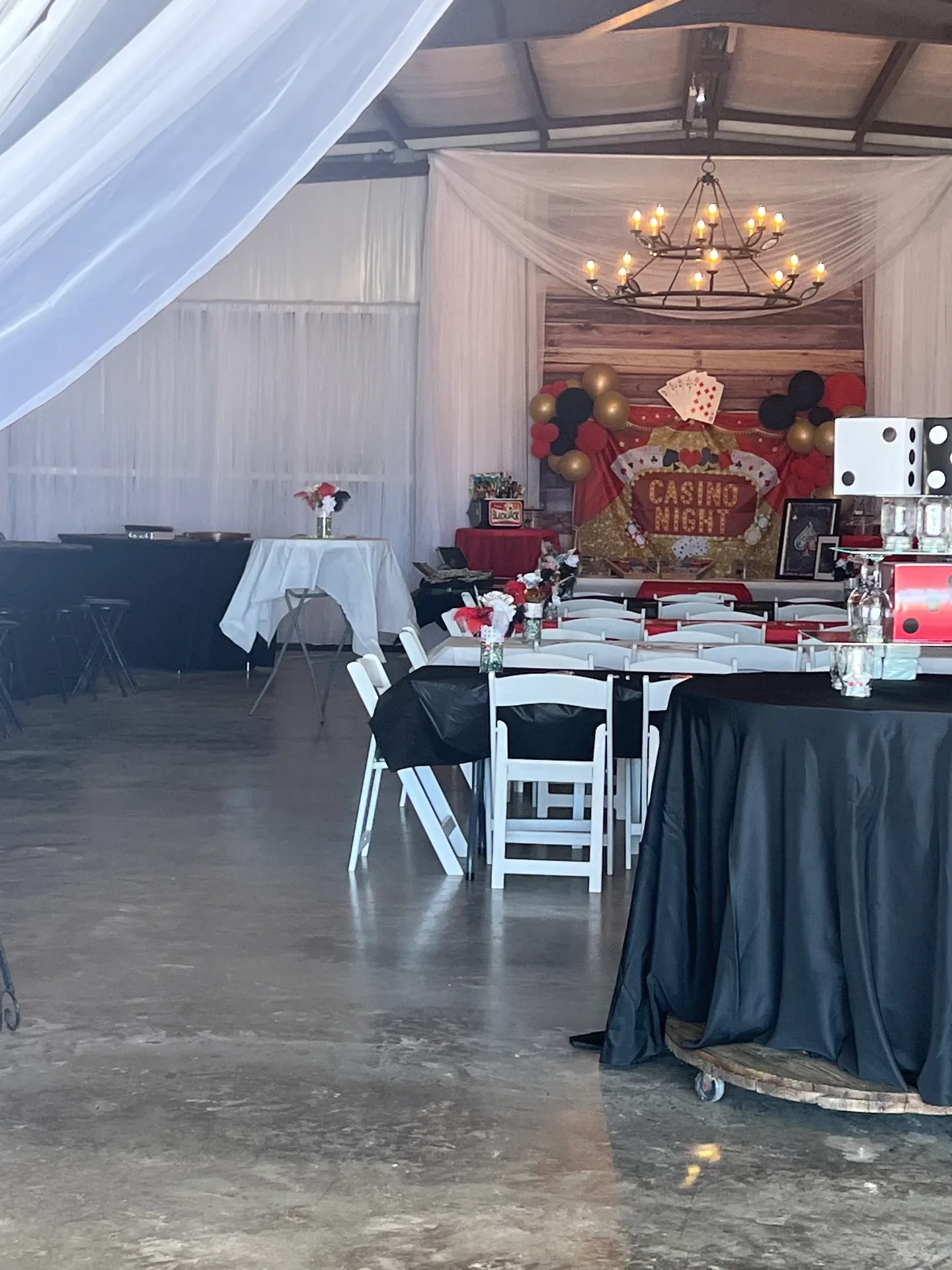 Wide interior view of the open event hall with casino tables, black linens and polished concrete floors during the Love Like Bailin event