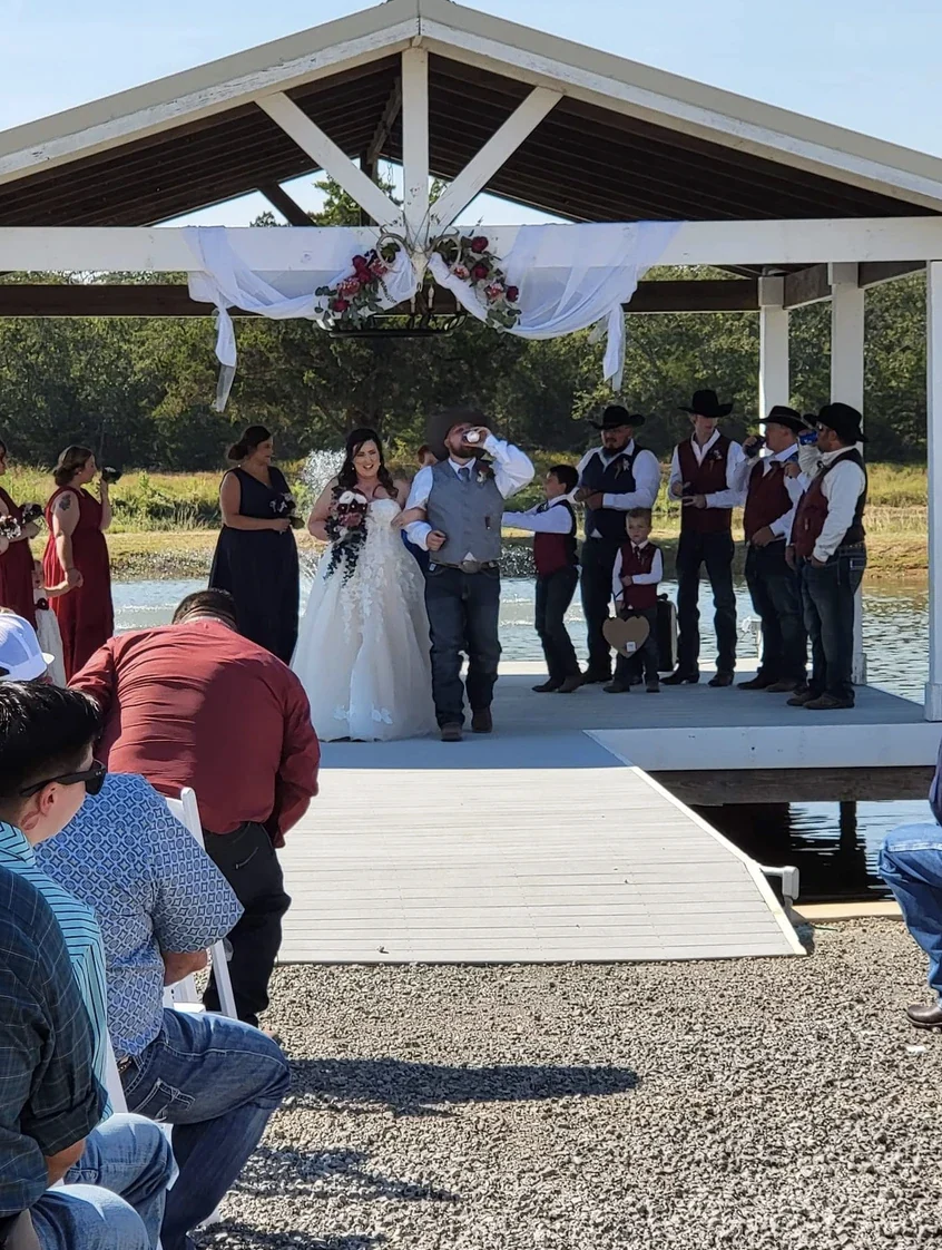 Bride and groom walking back up the aisle after their lakeside dock ceremony as guests look on