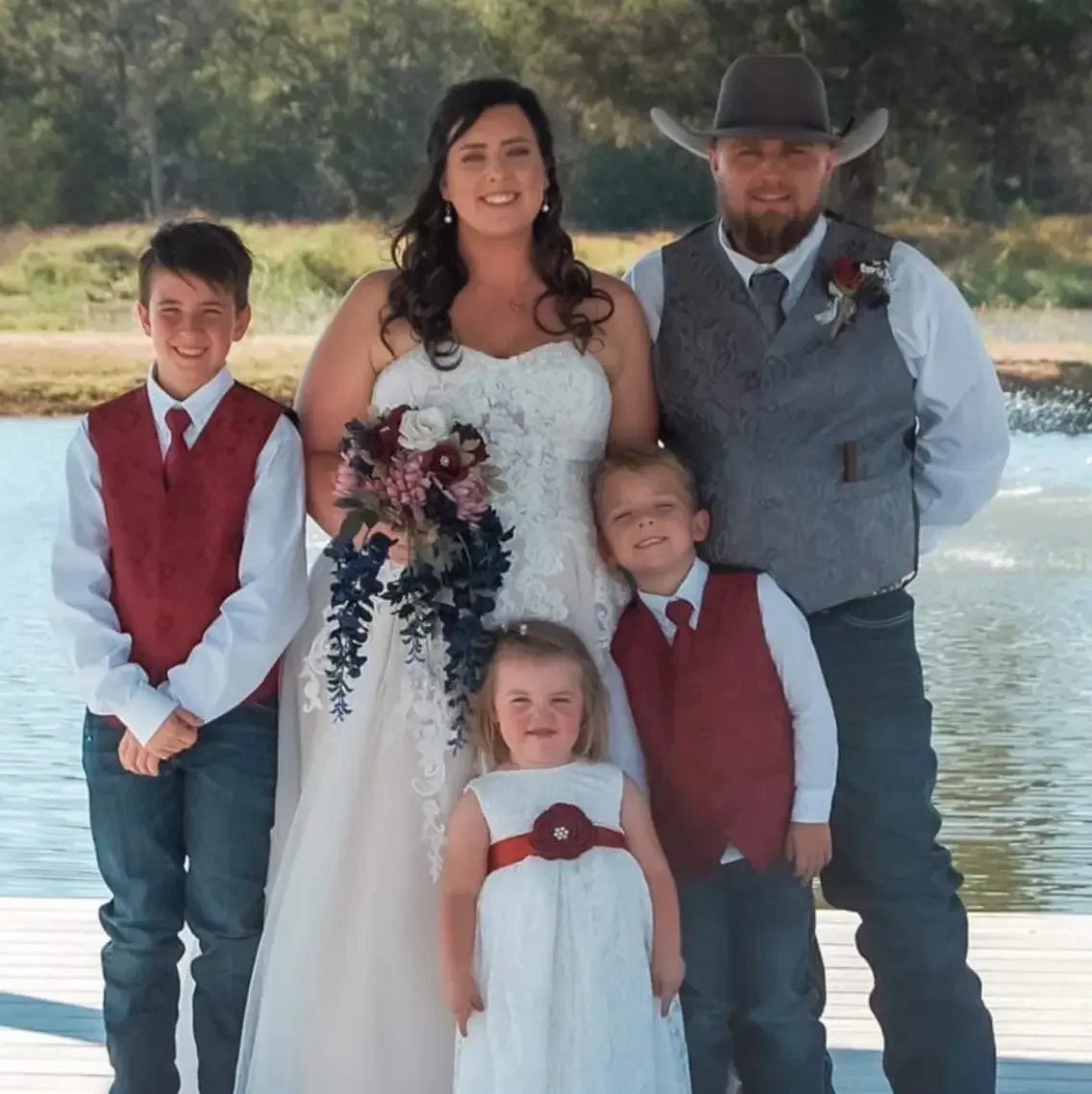 Bride, groom in a cowboy hat and three children posing on the dock over the lake at Reverie at Diamond D in Normangee, Texas