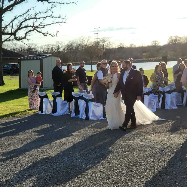 Newlyweds walking the recessional across the lawn beside the lake