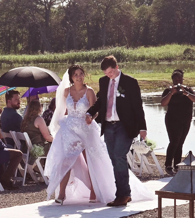 Bride and groom holding hands during their recessional along the lake at Reverie at Diamond D