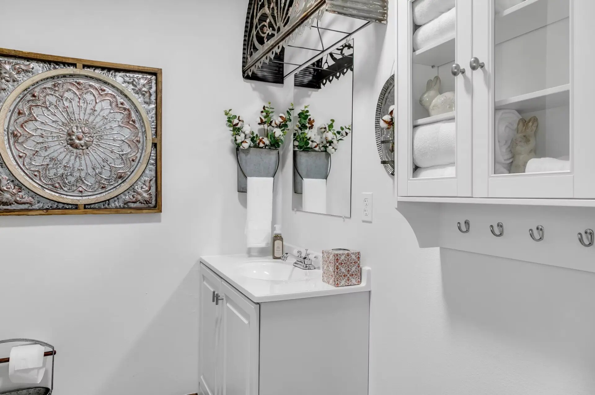 Farmhouse half bath with white vanity, fresh towels and antique tin wall art at Reverie at Diamond D