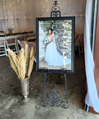 Framed bridal portrait on an iron easel beside pampas grass at Reverie at Diamond D
