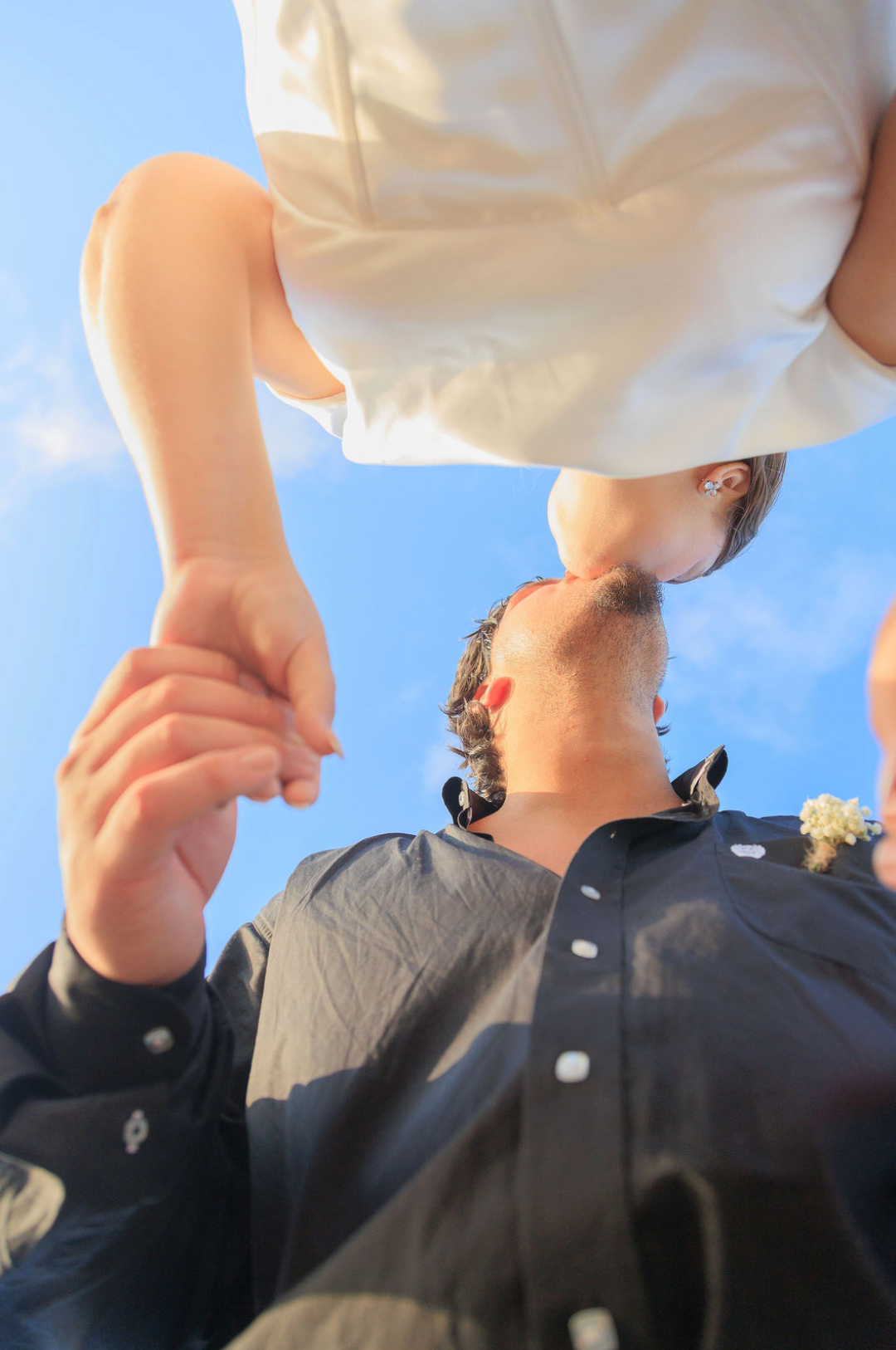 Jaelyn & Keelan's wedding at Reverie at Diamond D — low-angle portrait of the couple holding hands against the sky