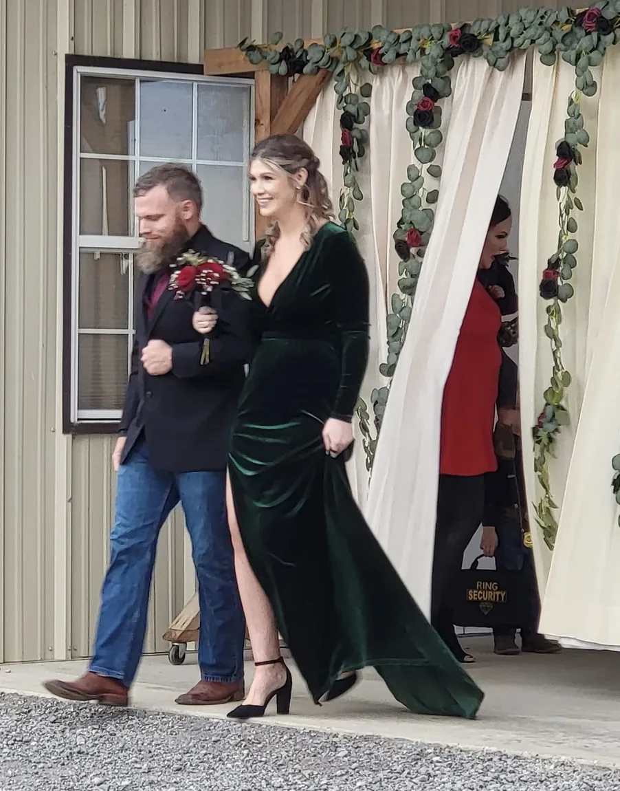 Bridesmaid in a deep green velvet gown escorted by a groomsman during the wedding processional at Reverie at Diamond D