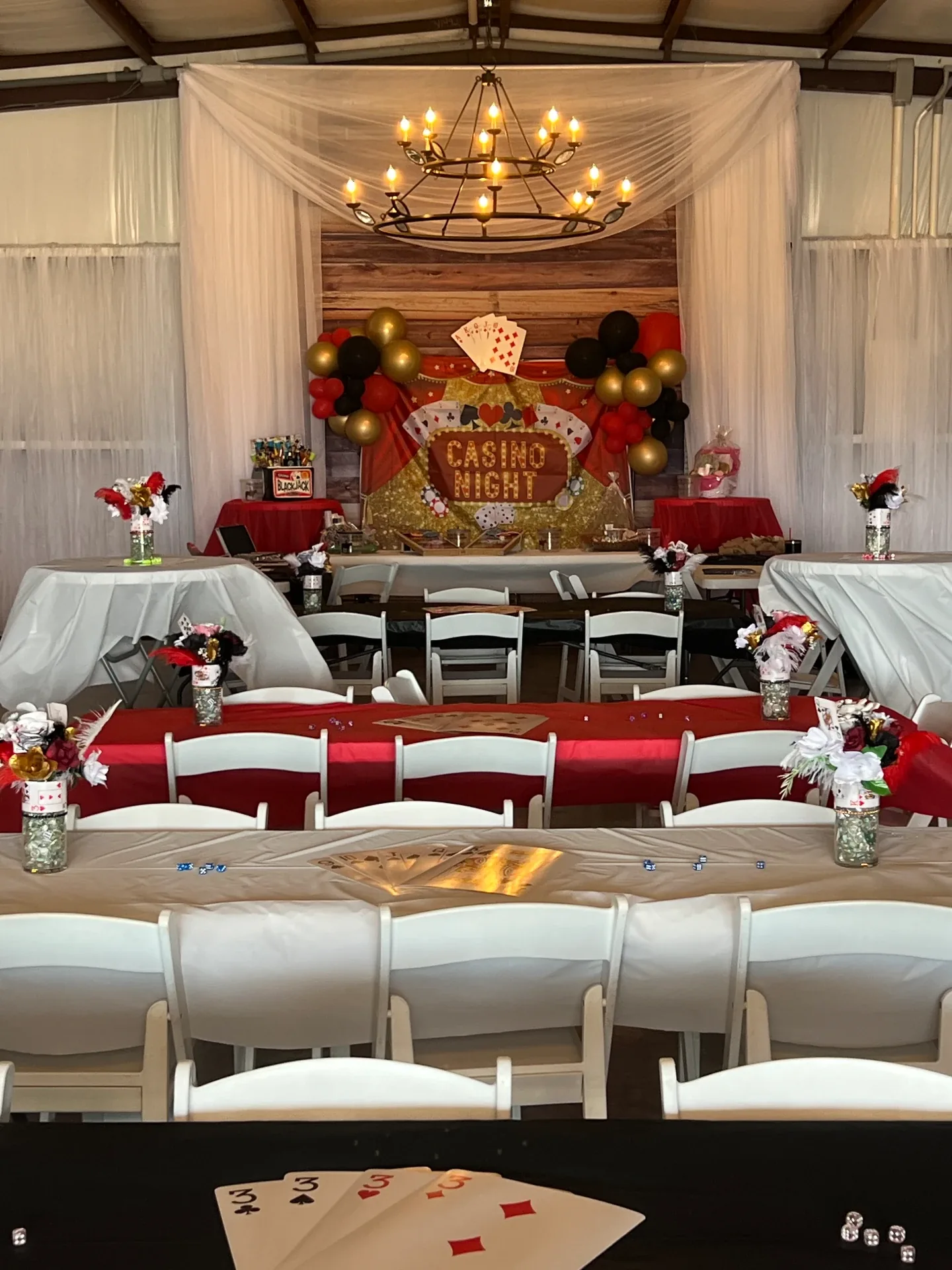 Red, black and gold balloon garland framing a lighted CASINO NIGHT sign on the reclaimed barn wood wall at the Love Like Bailin event