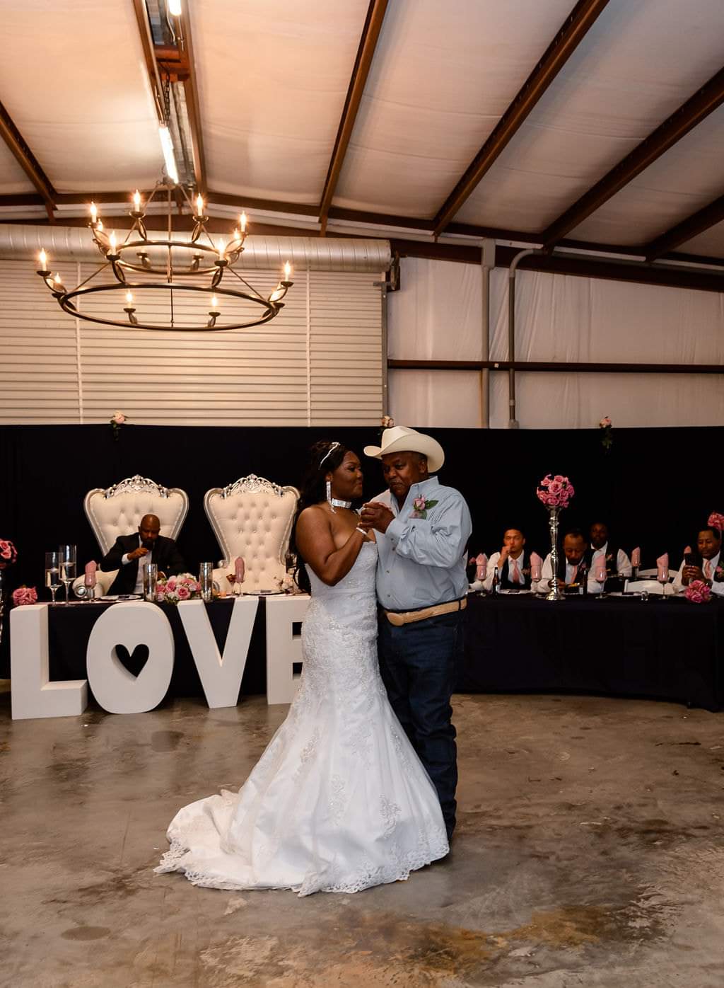 Father-daughter dance under the barn chandeliers beside the LOVE letters