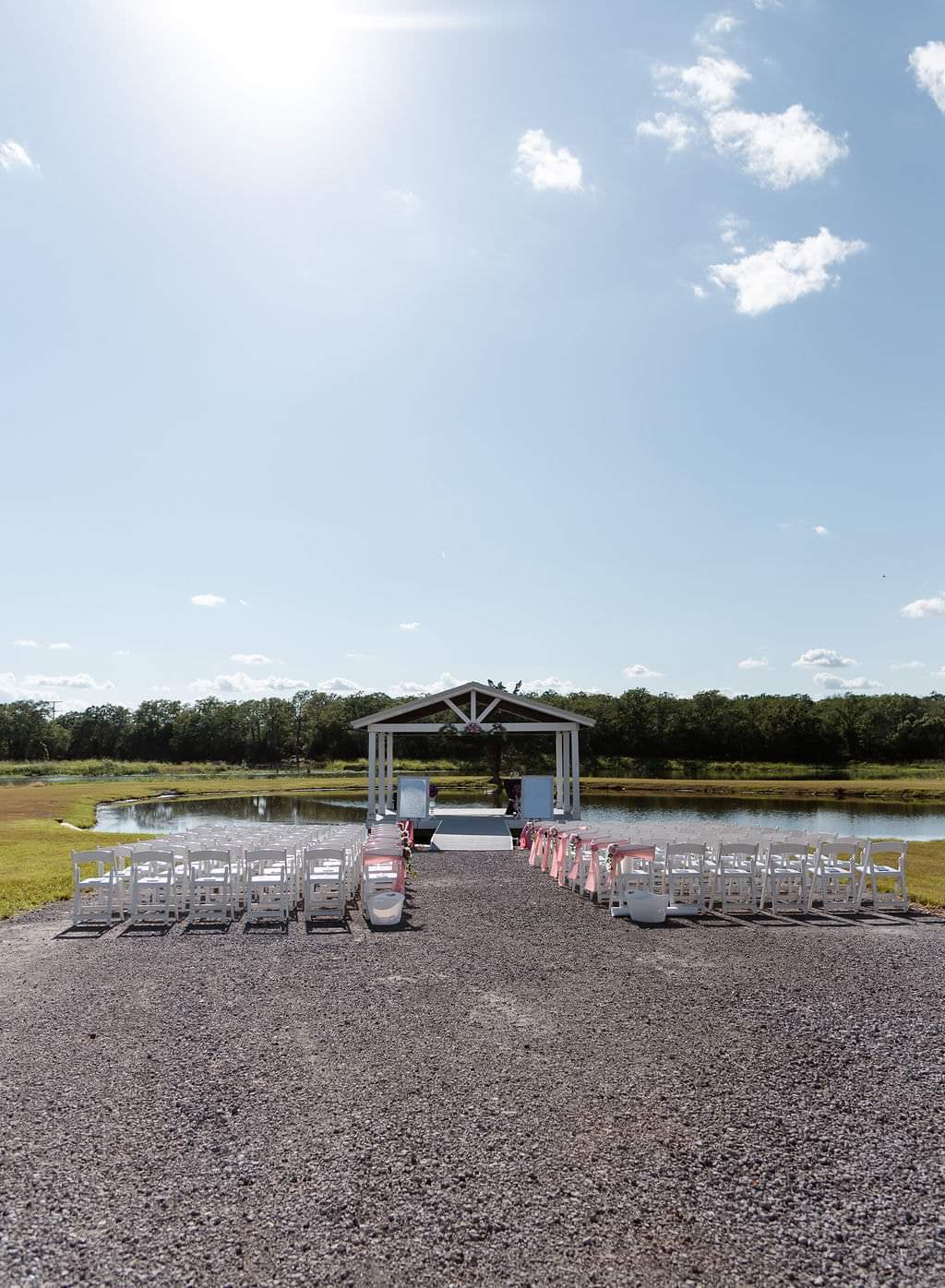 Wide view of white folding chairs set for a lakeside ceremony at the pavilion