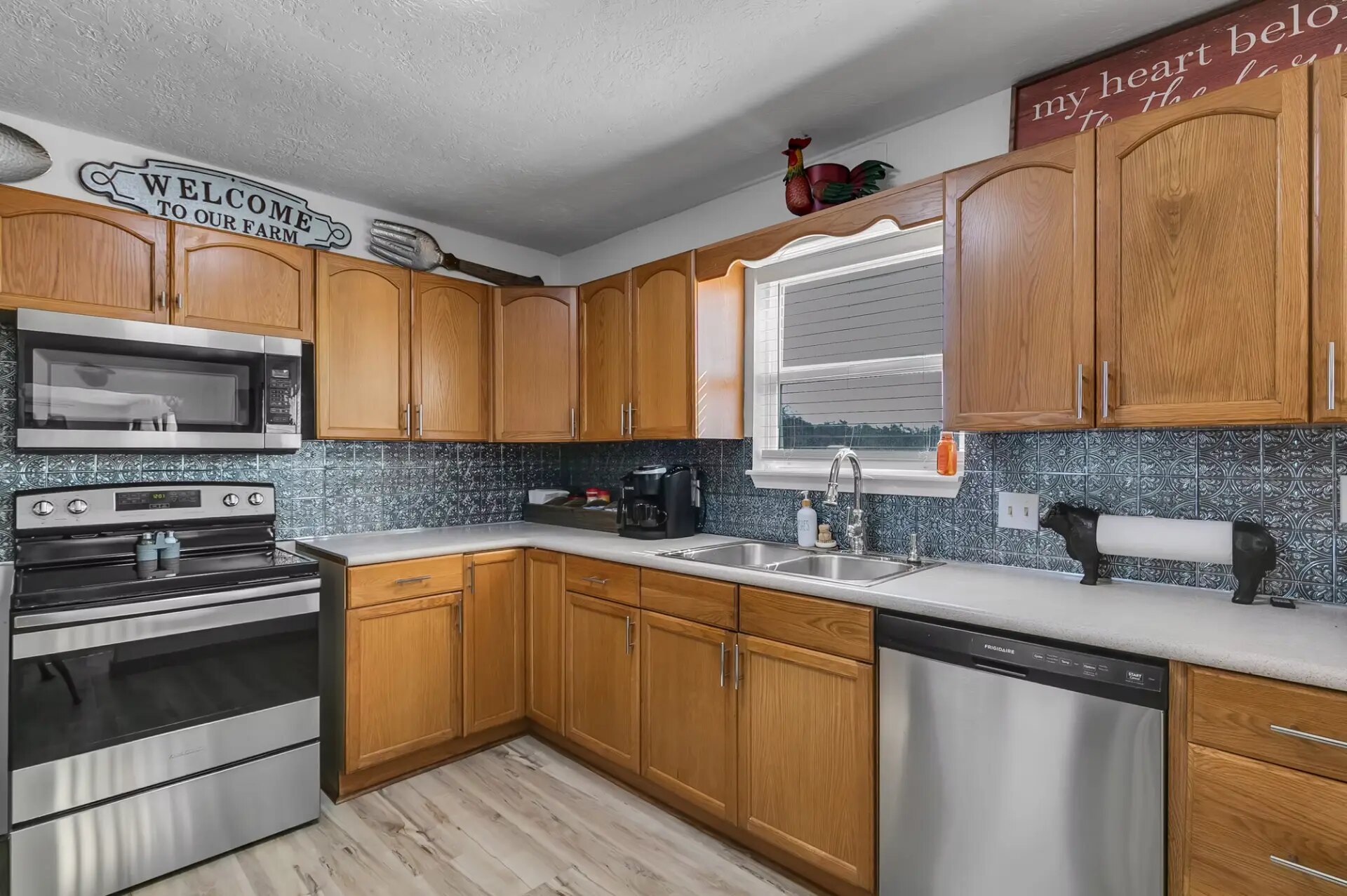 Full farmhouse kitchen with stove, dishwasher, coffee maker and tin backsplash at Reverie at Diamond D
