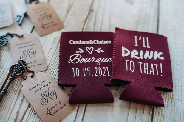 Burgundy custom koozies and vintage key thank-you favors on a whitewashed wood table