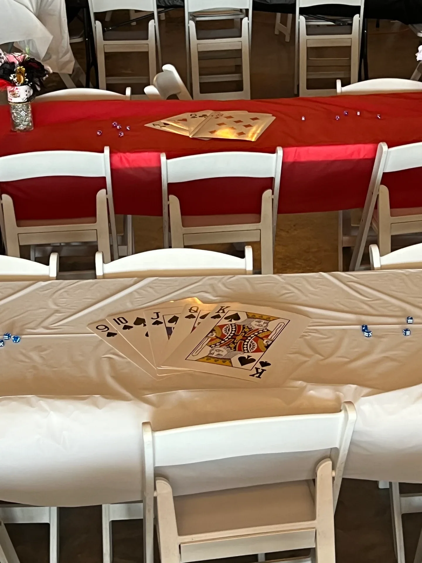 Oversized playing cards and scattered dice arranged as centerpieces on red and ivory table linens at the Love Like Bailin casino night