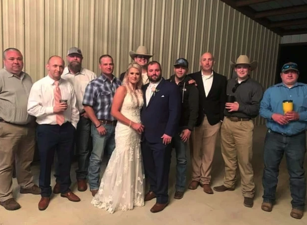 Bride and groom with groomsmen and friends outside the barn at night