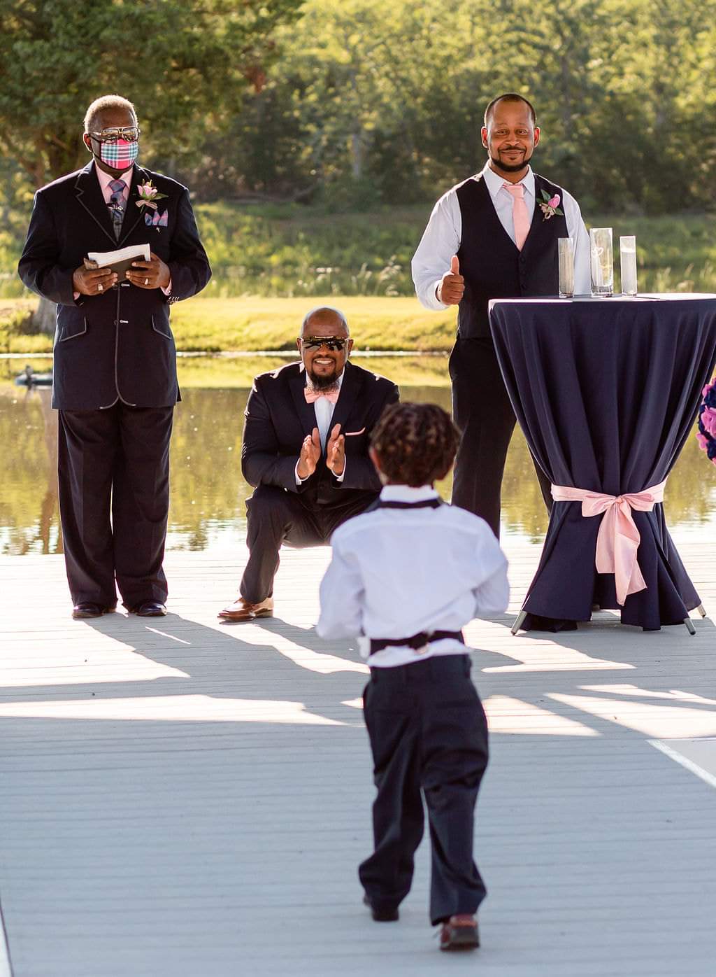 Ring bearer walking the lakeside dock toward the groom and officiant