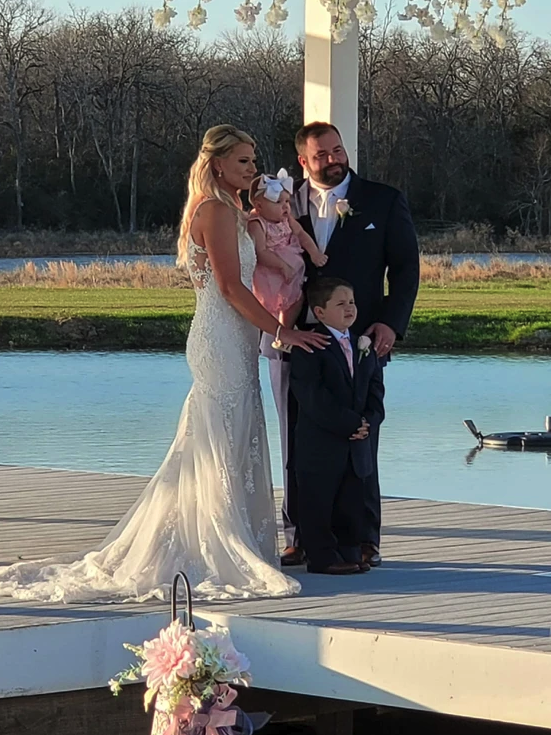Bride and groom with their children on the lakeside pavilion after their winter wedding ceremony