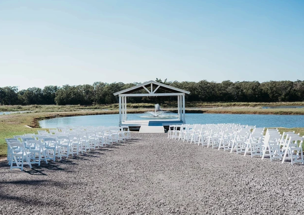 White garden chairs arranged in the round facing the lakeside ceremony pavilion