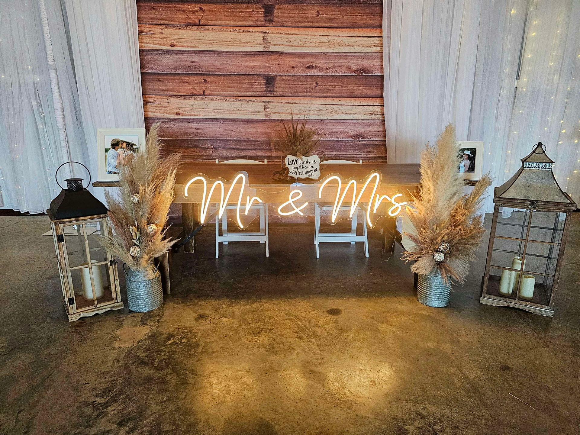 Sweetheart table with Mr and Mrs neon sign, pampas grass and lanterns against the reclaimed wood backdrop at Reverie at Diamond D