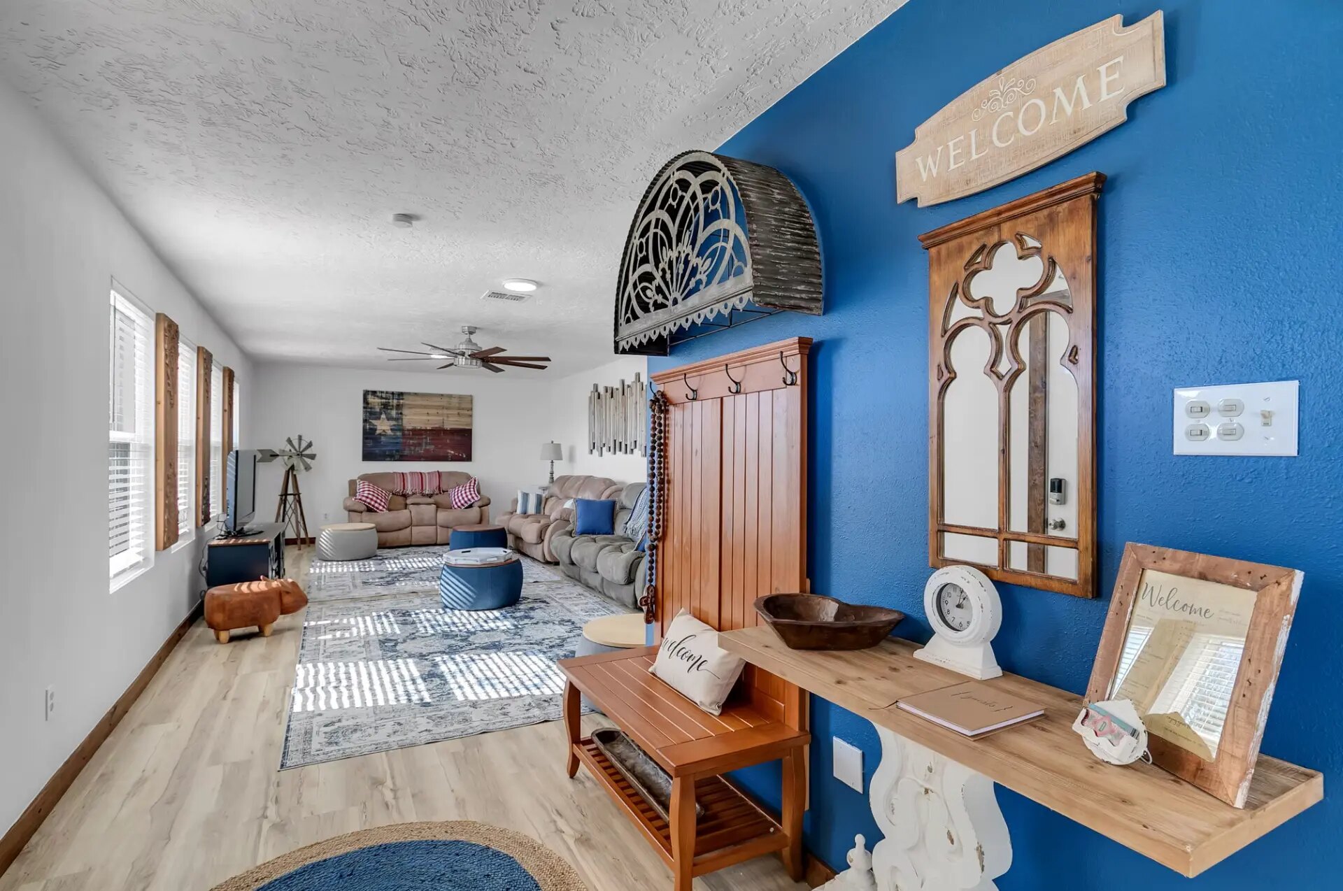 Farmhouse entry with a blue accent wall, welcome sign and coat rack looking into the living room at Reverie at Diamond D