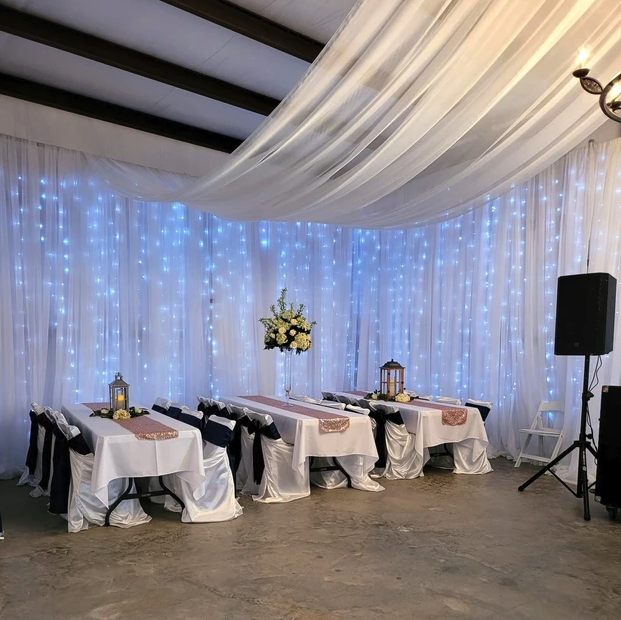 Head table set with rose gold runners in front of a twinkle-light draped backdrop