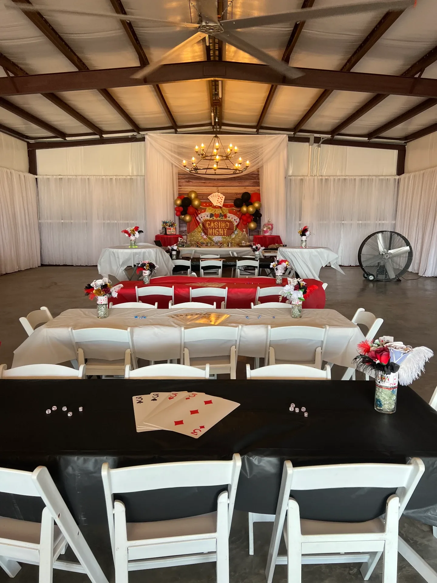 Blackjack and poker tables draped in red, black and ivory linens set for casino night at the Love Like Bailin Therapy Farm event