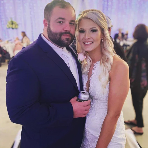 Bride and groom smiling together during their barn reception in front of the twinkle-light backdrop