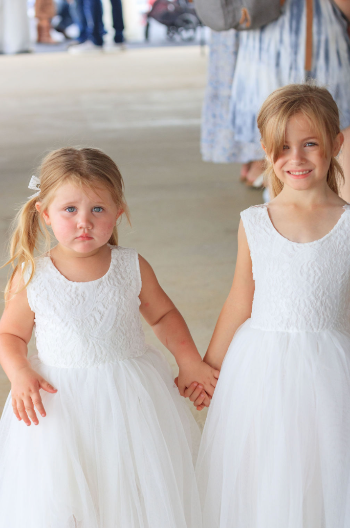 Jaelyn & Keelan's wedding at Reverie at Diamond D — two flower girls in white lace dresses holding hands