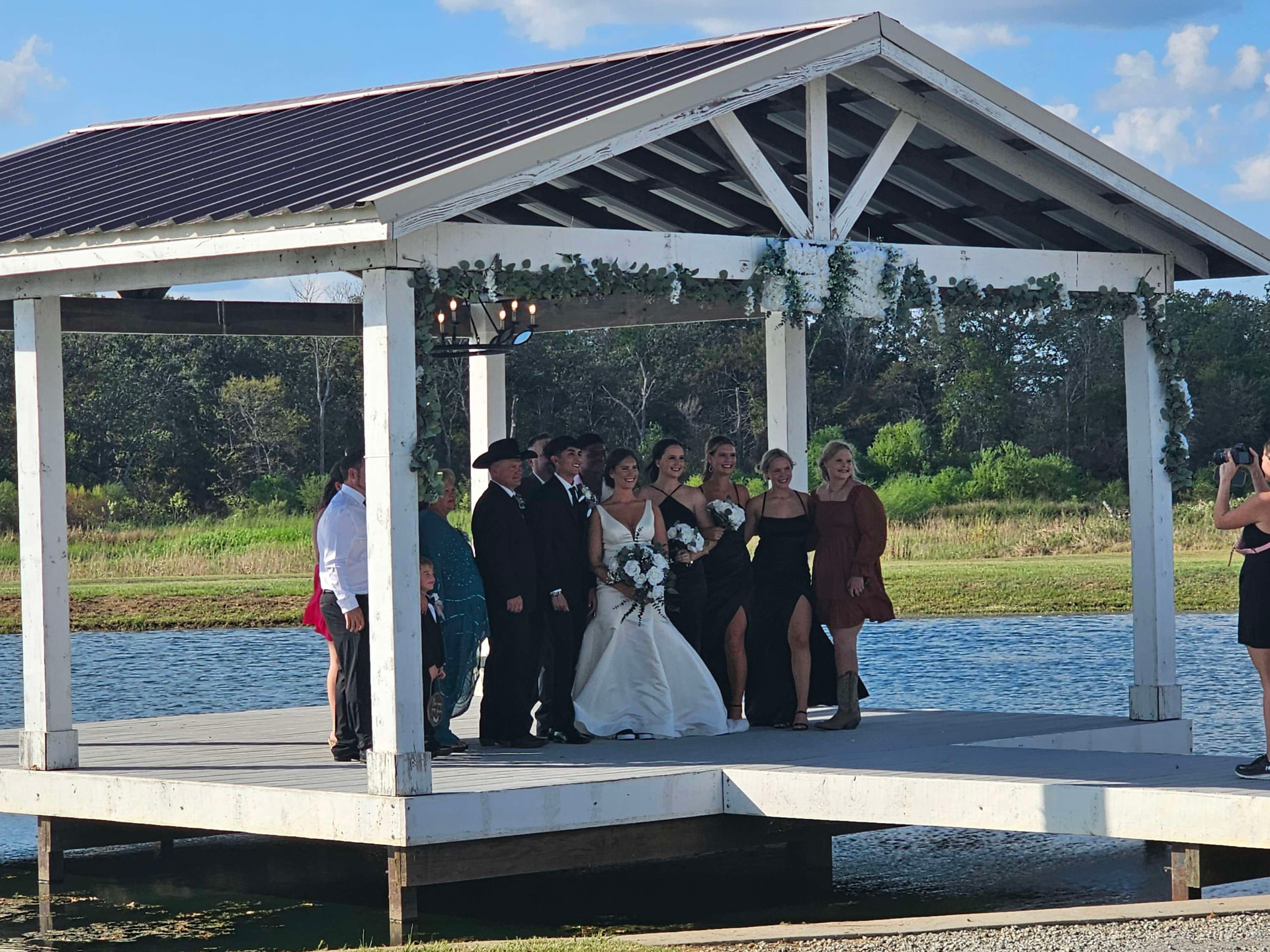 Bride with her wedding party laughing on the pavilion dock over the lake at Reverie at Diamond D