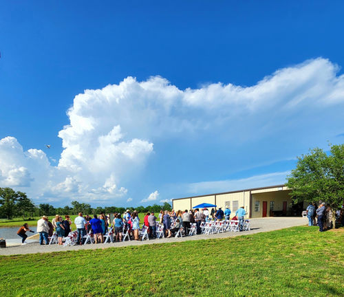 Wedding guests gathered outside the barn under big Texas clouds at Reverie at Diamond D