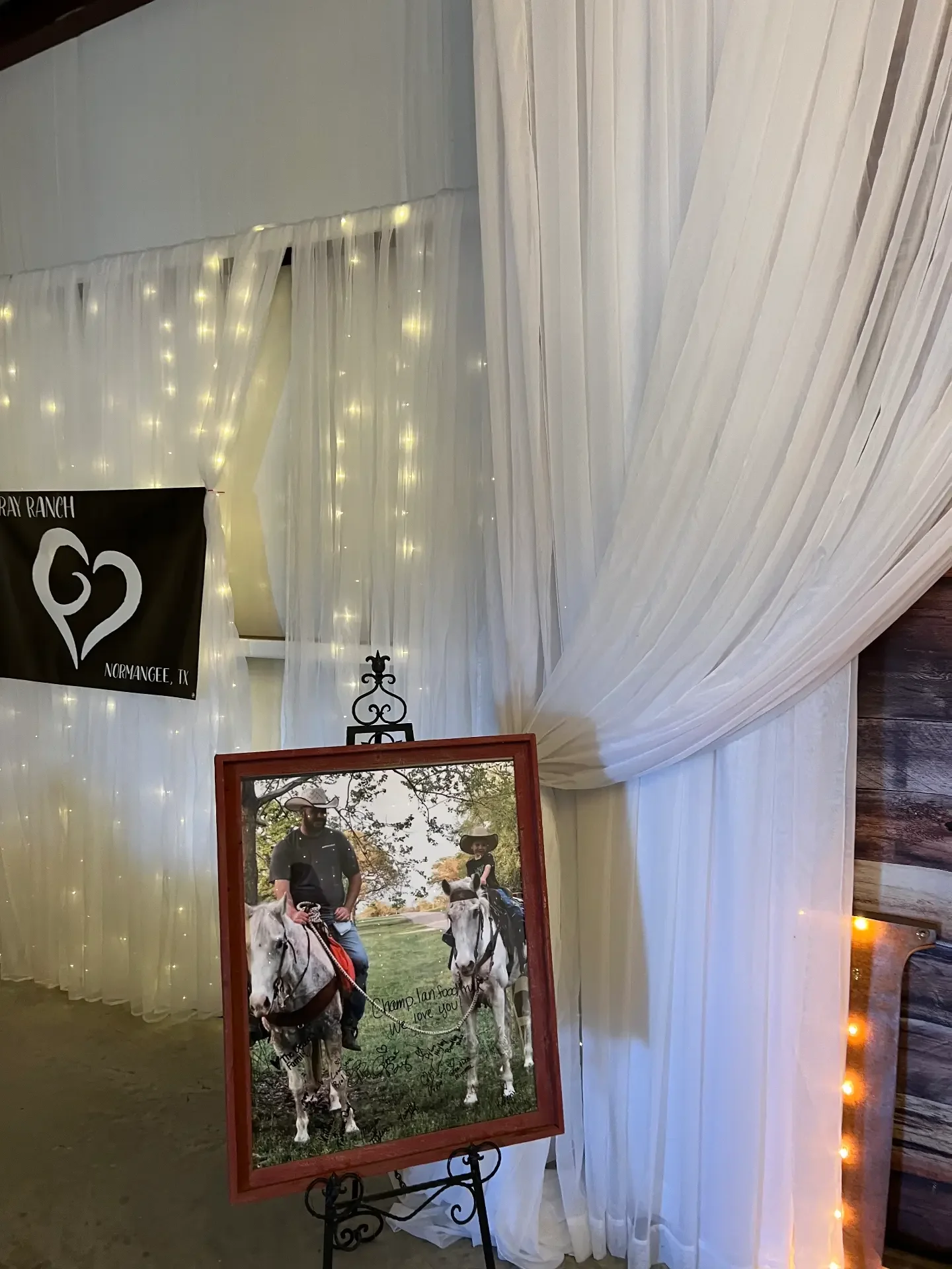 Framed signed photograph of two riders on horseback displayed on an iron easel beside a Gray Ranch banner at the Love Like Bailin Therapy Farm event
