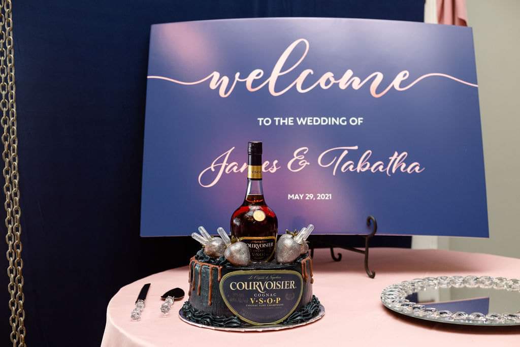 Navy welcome sign with a Courvoisier groom's cake on a blush table