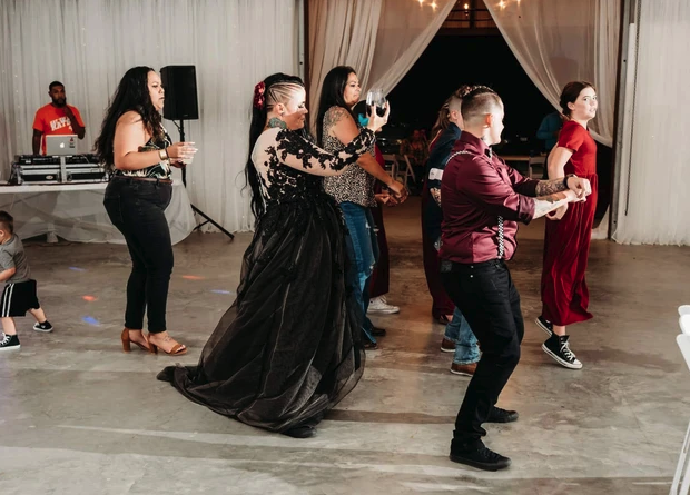 Guests line dancing with the bride in her black tulle gown on the reception floor