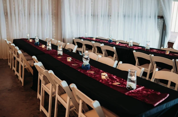 Long reception tables with black linens, burgundy velvet runners and floating candle centerpieces