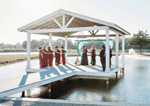Candace and Chelsea exchanging vows on the lakeside pavilion at Reverie at Diamond D in Normangee, Texas