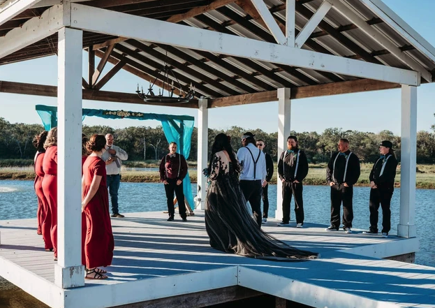 Lakeside dock ceremony with the wedding party gathered under the teal draped pavilion