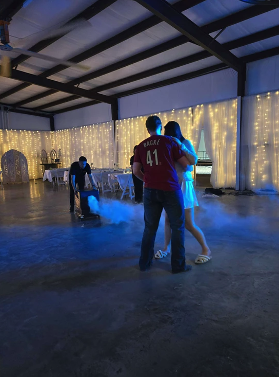 Couple's first dance surrounded by low fog and blue uplighting inside the barn at Reverie at Diamond D