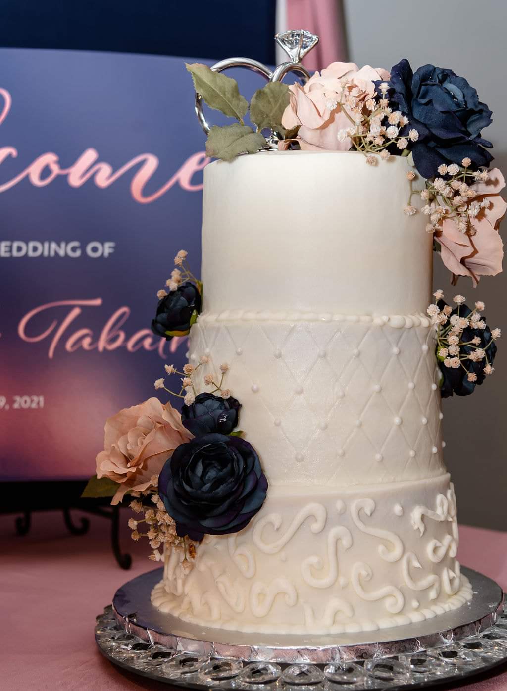 Three-tier white wedding cake with navy and blush florals
